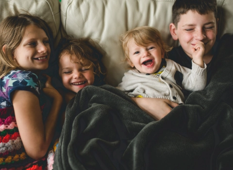 Enfants qui sont couchés dans un fauteuil et qui rigole.